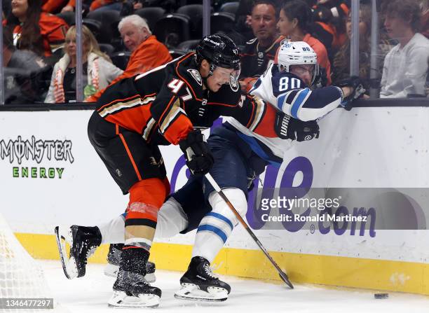 Hampus Lindholm of the Anaheim Ducks checks Pierre-Luc Dubois of the Winnipeg Jets in the third period at Honda Center on October 13, 2021 in...