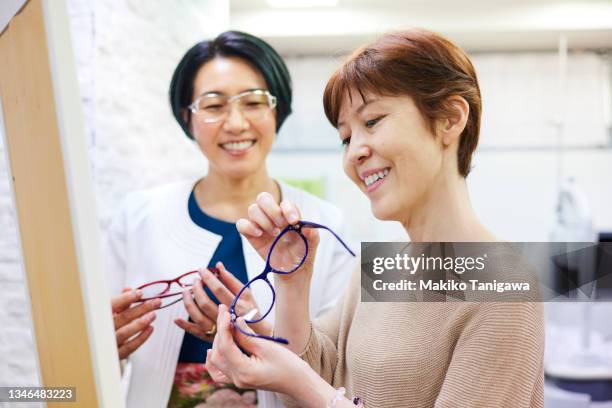 optometrist helping client to choose eyeglasses - buying eyeglasses stock pictures, royalty-free photos & images