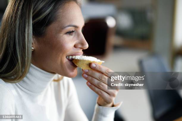 young happy woman having a meal at home. - bijten stockfoto's en -beelden