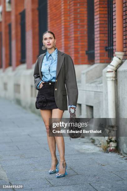 Pernille Teisbaek wears large gold and leather pendant earrings from Chanel, a blue denim shirt, a gray blazer jacket, black denim cargo short skirt,...