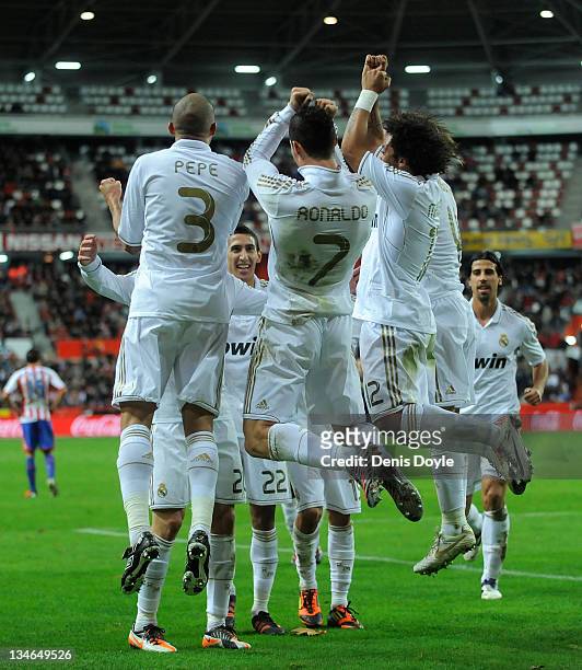 Cristiano Ronaldo of Real Madrid celebrates with Pepe and Marcelo after scoring Real's second goal during the La Liga match between Sporting Gijon...