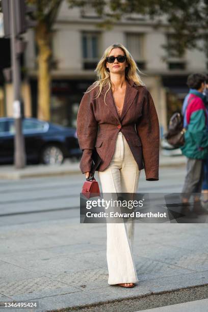 Anne-Laure Mais wears black sunglasses from Ray Ban, a beige braided wool V-neck t-shirt, a brown oversized blazer jacket, high waist beige tweed...