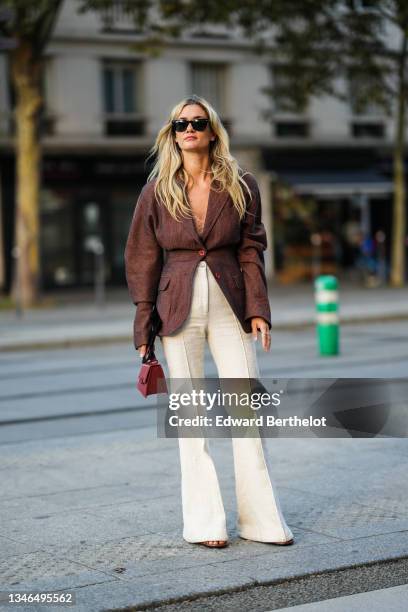 Anne-Laure Mais wears black sunglasses from Ray Ban, a beige braided wool V-neck t-shirt, a brown oversized blazer jacket, high waist beige tweed...