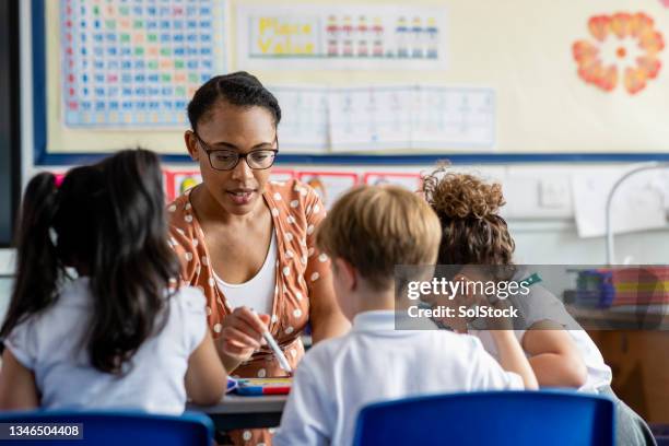 assisting her students - primary school stock pictures, royalty-free photos & images