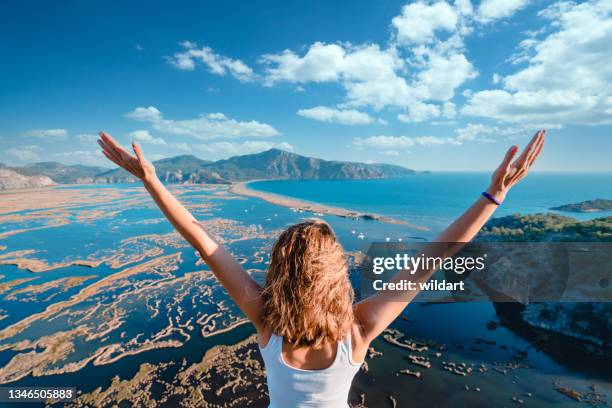 beautiful woman open her arms while watching beautiful scenery of iztuzu beach and dalyan delta in mugla, turkey - delta i stock pictures, royalty-free photos & images