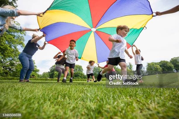 playing with the parachute in p.e - parachute stock pictures, royalty-free photos & images