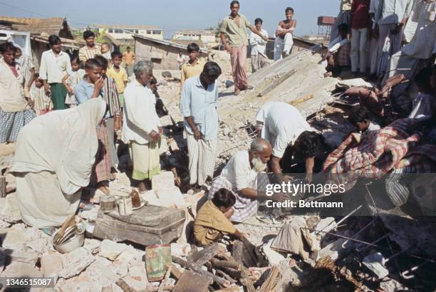 Victims of shelling search for their belongings amid the ruins of their homes following attacks by guerillas during the Bangladesh Liberation War in...