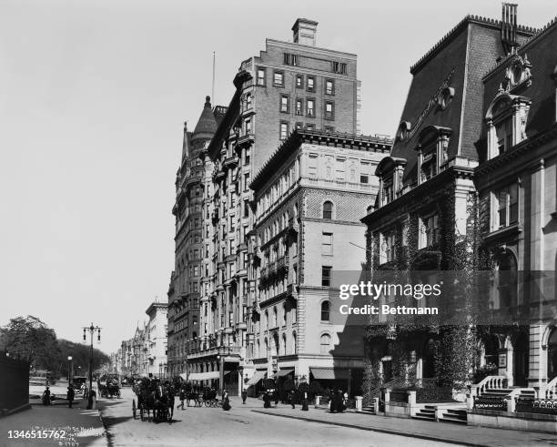 View pedestrians and carriages at Fifth Avenue and 57th Street, looking north towards Central Park, in the borough of Manhattan in New York City, New...