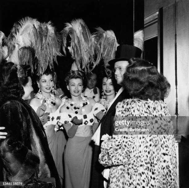 Showgirls in costume stand with an unspecified man in a top hat and a woman in a fur coat as the doors are closed following an emergency order...