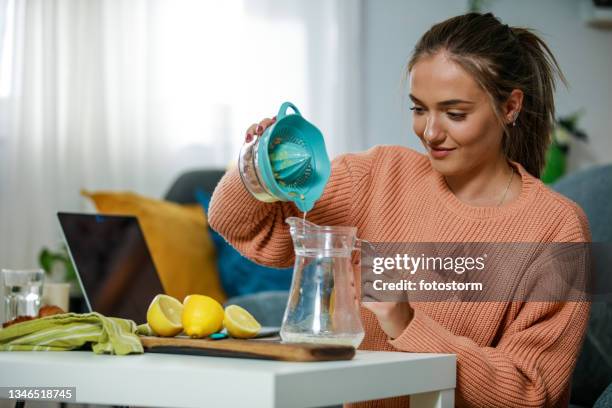 lächelnde junge frau, die eine limonade macht - lemon juice stock-fotos und bilder