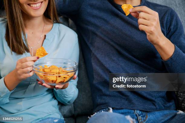 cut out shot of couple snacking on tortilla chips while watching tv - tortilla chip stock pictures, royalty-free photos & images
