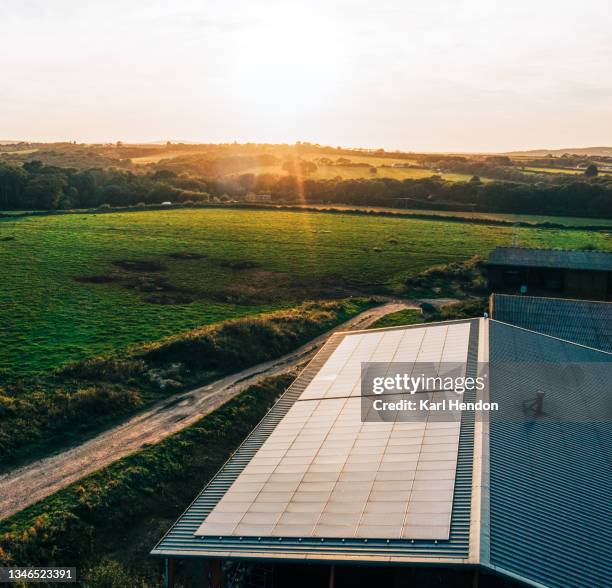solar panels on a barn roof at sunset - stock photo - rooftop farm stock pictures, royalty-free photos & images