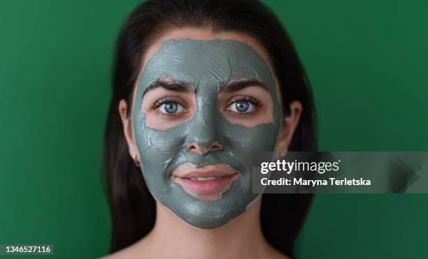 young woman with a clay mask on her face. - gesicht kosmetik maske stock-fotos und bilder