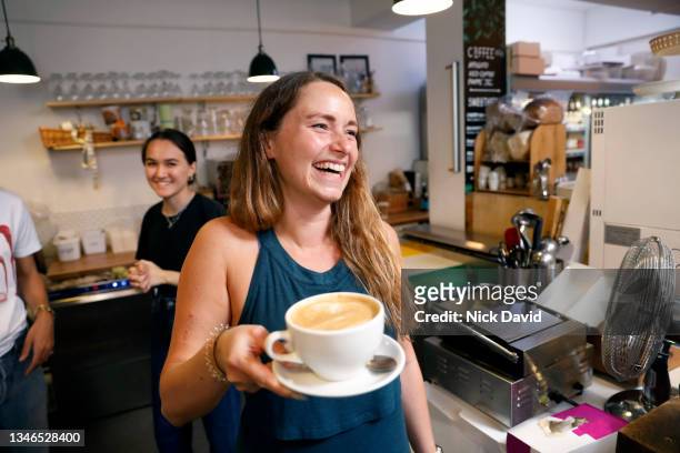 a smiling waitress serving a coffee - restaurateur photos et images de collection