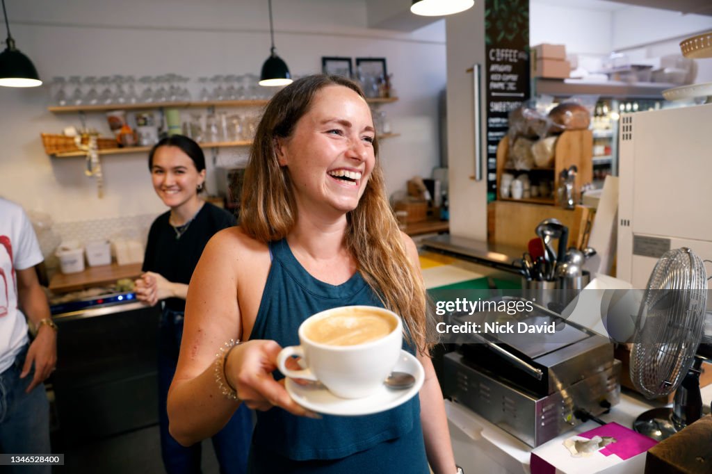 A smiling waitress serving a coffee