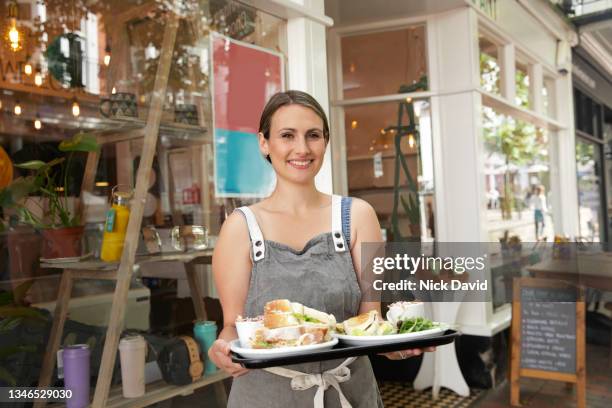 cheerful cafe owner standing outside her cafe - sandwich shop stock pictures, royalty-free photos & images