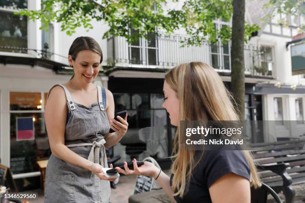 a waitress taking a contactless payment from a customer - cafe culture uk stock pictures, royalty-free photos & images