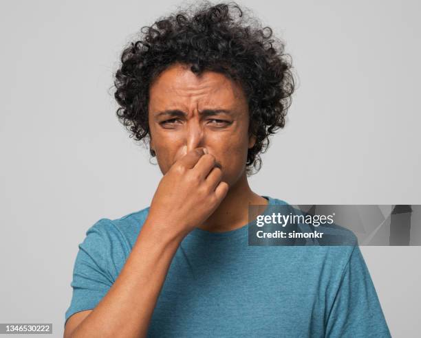 close-up of young man holding nose - unpleasant smell stock pictures, royalty-free photos & images