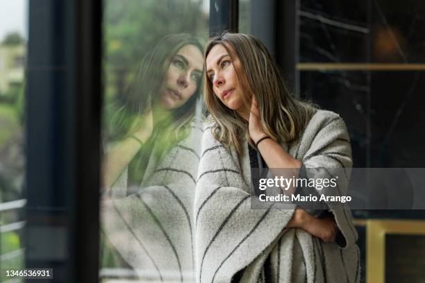 sehr gelangweilte und traurige frau, die sich an das fenster ihres hauses lehnt und für so viel zeit der isolation wegschaut - sick window stock-fotos und bilder