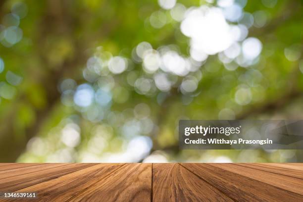 backgrounds: empty wooden table with defocused green lush foliage at background - picnic table top stock pictures, royalty-free photos & images