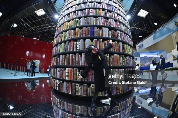 Woman poses for a photo near of column of books during of the Turin International Book Fair on October 14, 2021 in Turin, Italy. The Turin...
