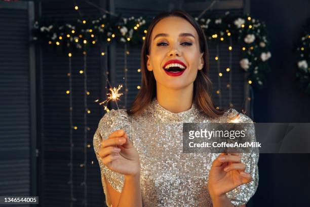 feliz mujer hermosa sosteniendo una chispa festiva entre la noche de navidad - fiesta fotografías e imágenes de stock