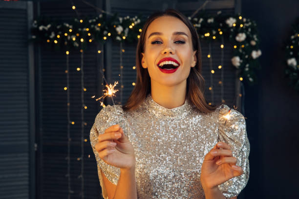 happy beautiful woman holding festive sparkler among christmas night - mulher bonita imagens e fotografias de stock