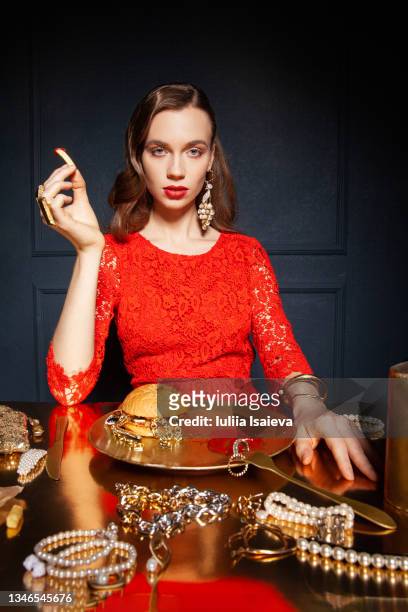 luxury woman eating fast food on dark background - gold dress 個照片及圖片檔