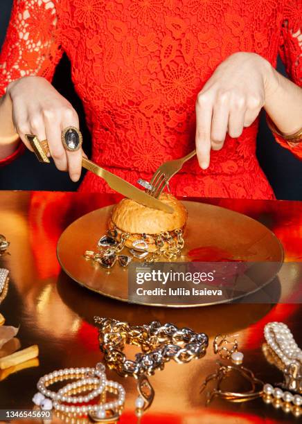 crop woman eating burger with jewelry on dark background - plate eating table imagens e fotografias de stock
