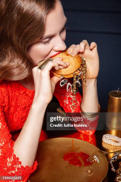woman in red dress eating burger with jewelry - fine jewelry stock pictures, royalty-free photos & images