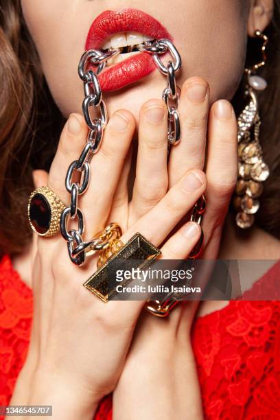 rich woman with jewelry in mouth on dark background - rhinestone stockfoto's en -beelden