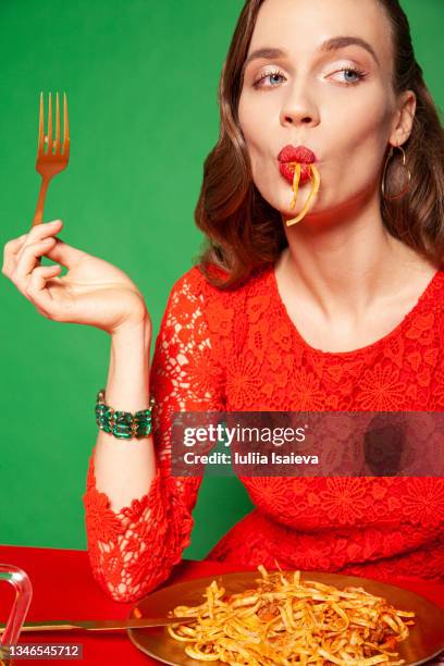 stylish woman in red dress eating spaghetti - aziatische-noedels stockfoto's en -beelden