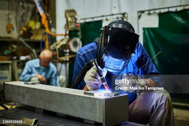 father and son working in a small welding factory - tradesman toolkit stock pictures, royalty-free photos & images