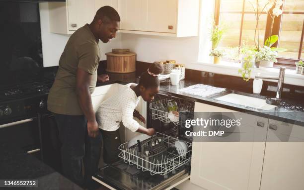 full length shot of an adorable little girl and her father packing the dishwasher in the kitchen at home - black man full length stock pictures, royalty-free photos & images