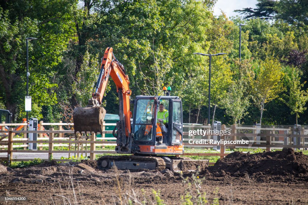 Mann, der einen kleinen Bagger betreibt, der einen neuen Parkplatz am Stadtrand von Cirencester, Gloucestershire, England, am 6. Oktober 2021 ausgräbt.