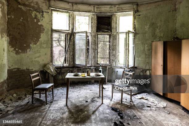 living room in bad condition in an abandoned building - geisterstadt stock-fotos und bilder