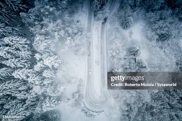 aerial view of car driving in the snow on mountain road - haarnadelkurve stock-fotos und bilder