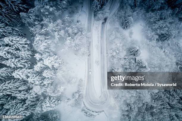 aerial view of car driving in the snow on mountain road - hairpin curve stock-fotos und bilder