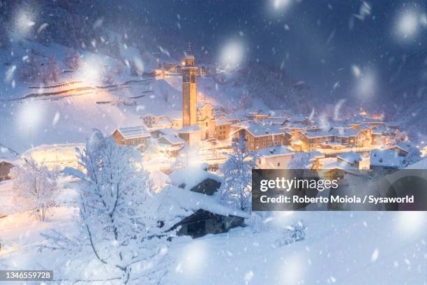 snowflakes covering the alpine village at christmas - colorful sunset stock-fotos und bilder