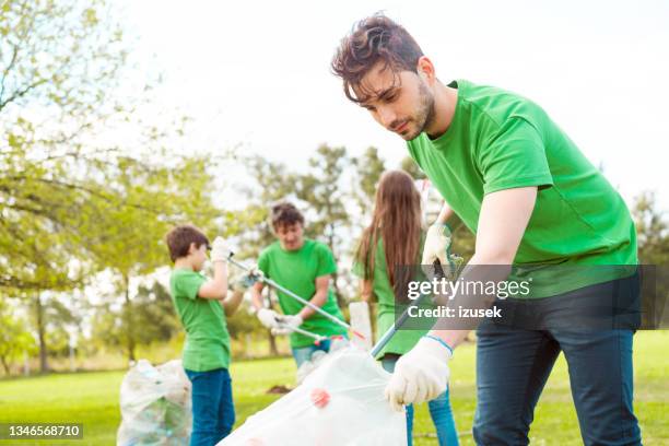 male volunteer collecting litter in plastic bag - claw machine bildbanksfoton och bilder