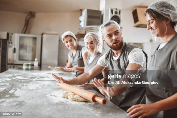 male baker showing female apprentices how to use rolling pin - intern stock pictures, royalty-free photos & images