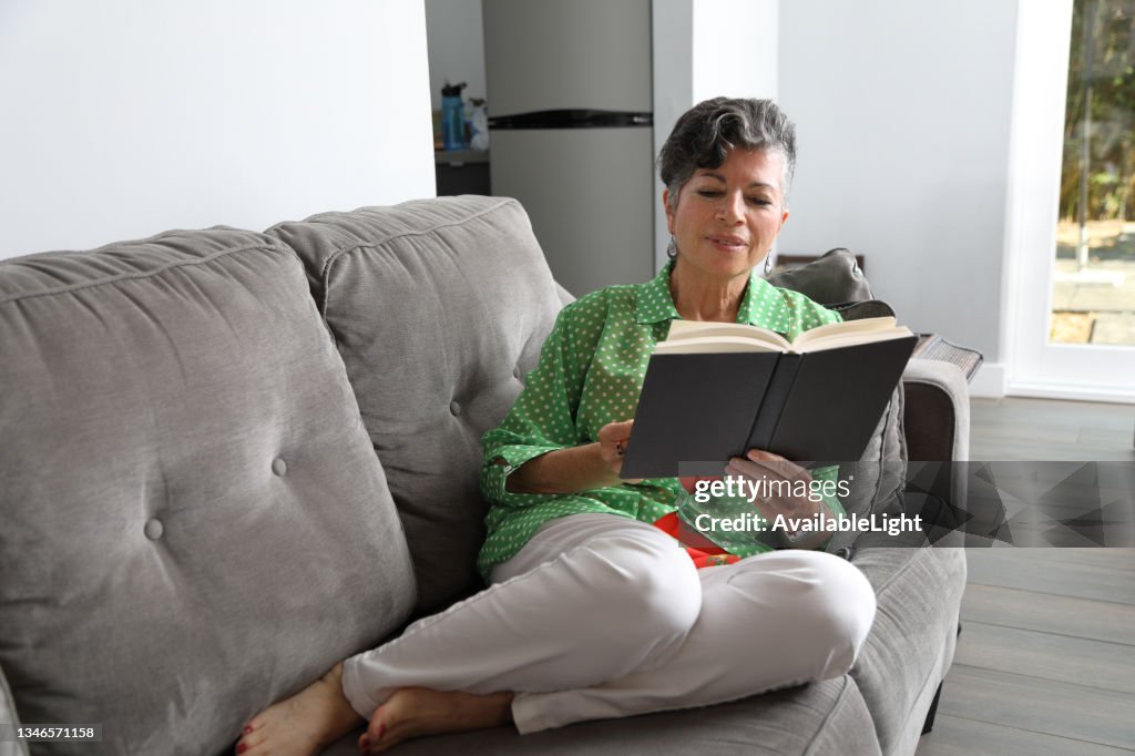 Hispanic Woman Reads Book at Home Reverse Angle