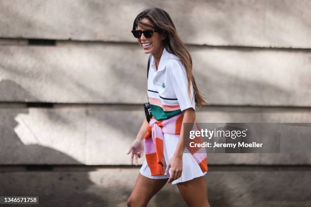 Fashion Week Guest wearing a white, green and rose Lacoste shirt and a white skirt with a orange and pink pullover outside Lacoste Show on October...