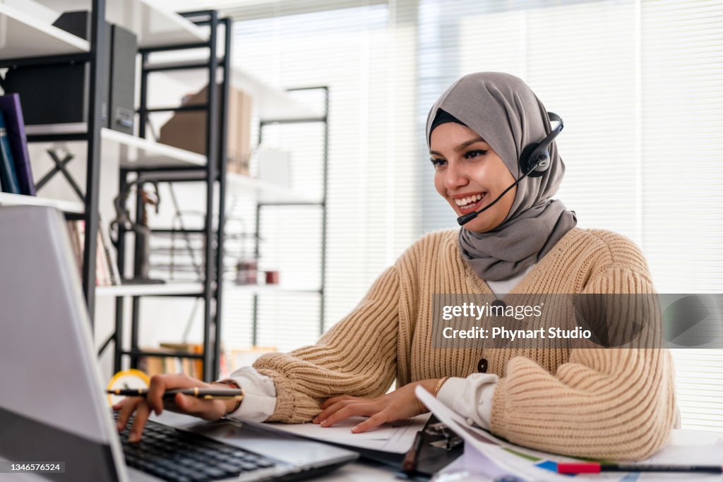 Black Islamic Lady In Hijab And Headset Having Video Call On Laptop