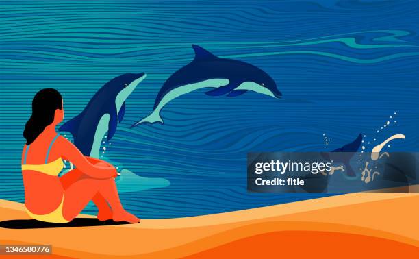 the girl in bikini sat on the beach watching the dolphins jump out of the sea - dolphins stock illustrations