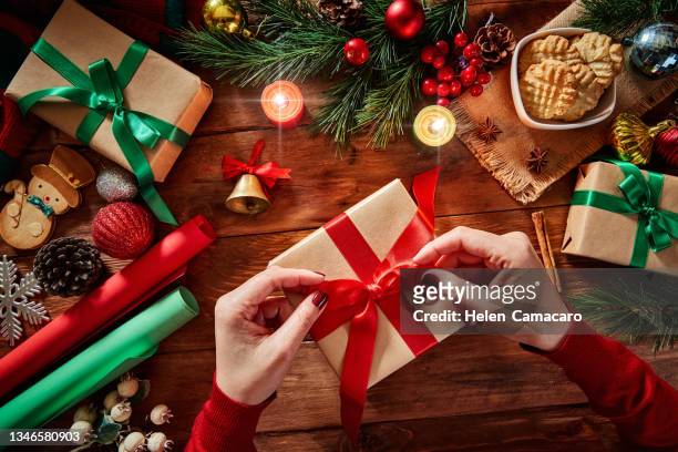 top view of woman hands with christmas present on rustic wooden table - schokonikolaus stock-fotos und bilder