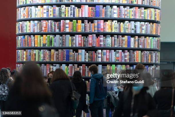 Visitors wearing face masks view book on display during the Turin International Book Fair on October 14, 2021 in Turin, Italy. The Turin...