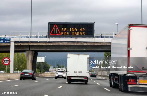 car point of view driving. cars and trucks driving with a light signal on a highway warning of a detour due to road works. - trucks on queue stock pictures, royalty-free photos & images