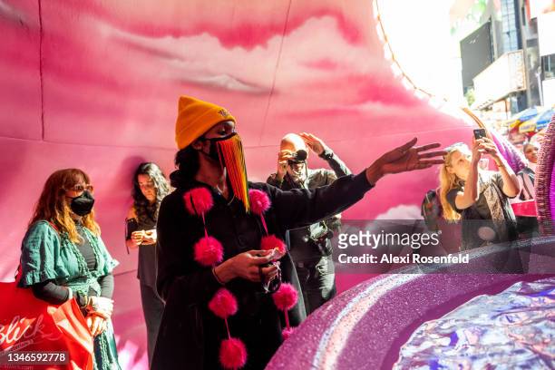 Woman throws a special coin into ‘A Fountain for Survivors’ by artist Pamela Council during the unveiling in Times Square on October 14, 2021 in New...