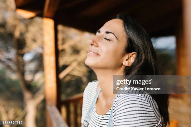 woman breathing fresh air from a wooden house in the nature - deep breathing stock pictures, royalty-free photos & images